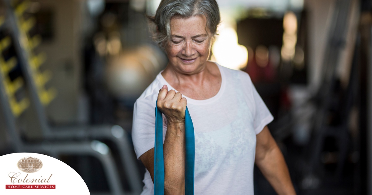 An older woman uses a resistance band to exercise, representing how staying active can help older adults keep their blood pressure in a healthy range.